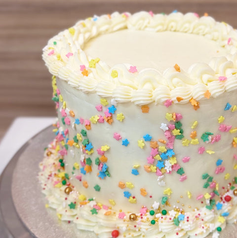 Tarta de vainilla con dulce de leche, decorada con grajeas de colores.
